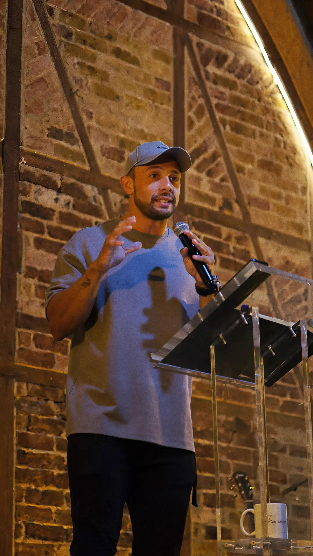 The pastor preaches at the lectern in front of a brick wall
