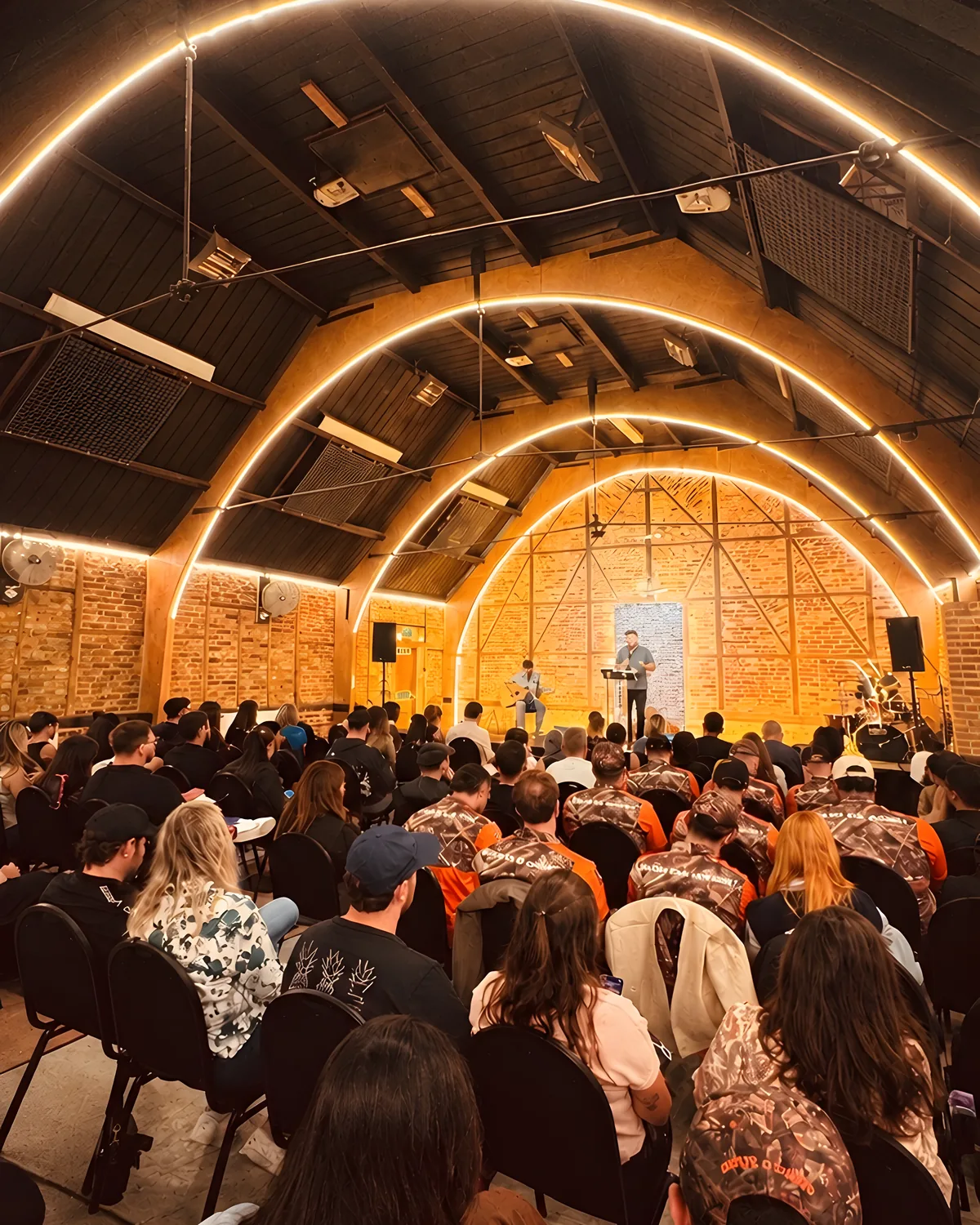 A full room at Hillside Church on a Monday night, lit arches over the stage