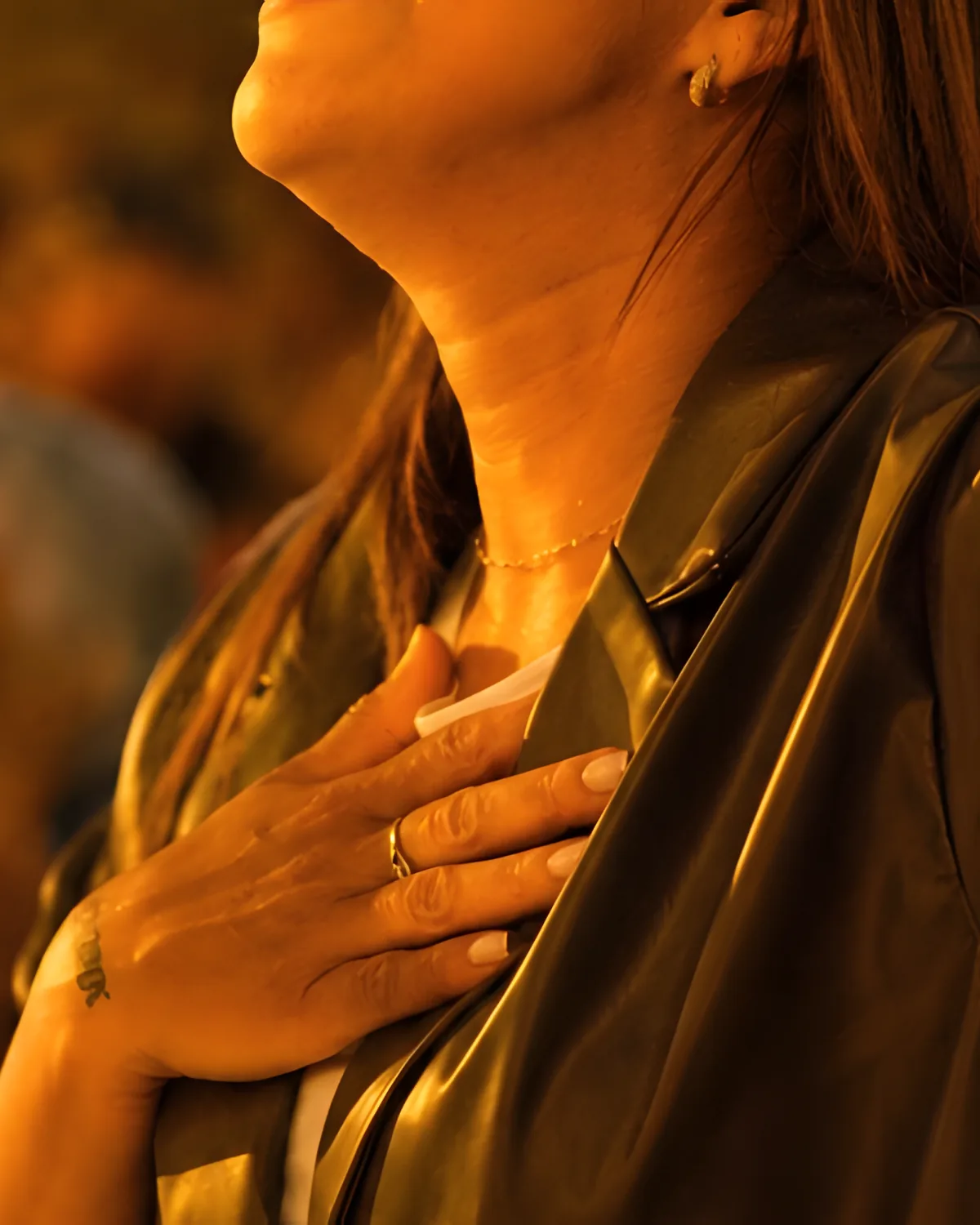 A woman worships with one hand on her heart and the other raised