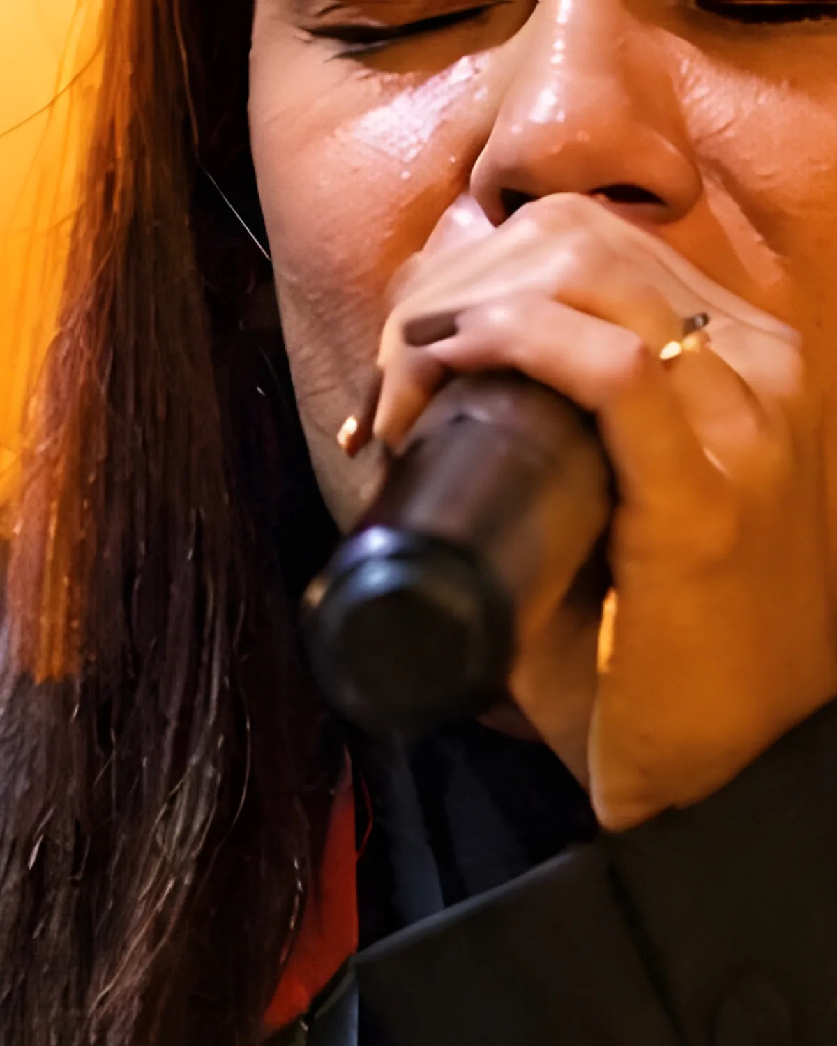 A worship leader sings with her eyes closed and her arm outstretched